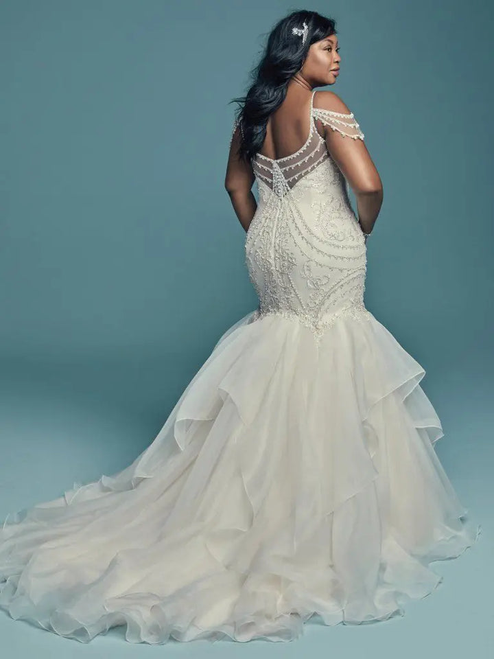 Woman wearing a white wedding dress with intricate detailing on a blue background