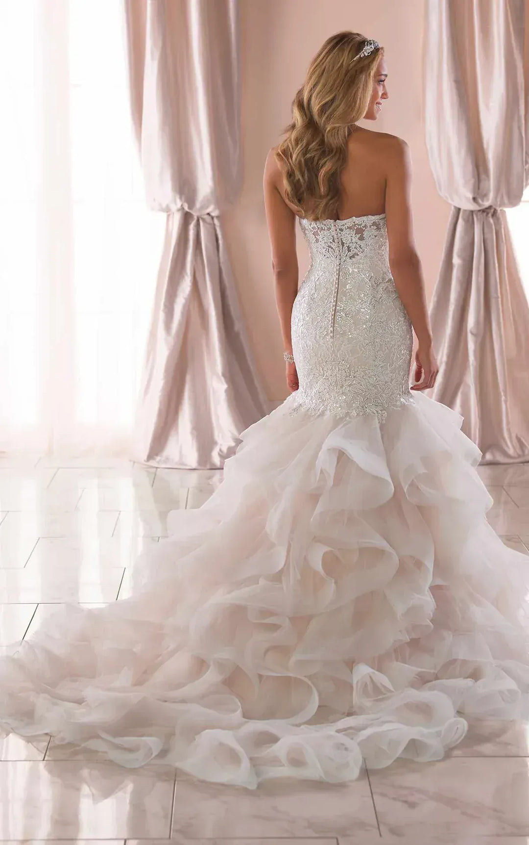 full back of stella york 6750 blush tulle fit and flare wedding dress with a tiered ruffle skirt and chapel length train