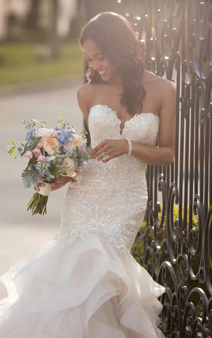 close up of stella york 6750 blush tulle fit and flare wedding dress with a tiered ruffle skirt and beading on the bodice