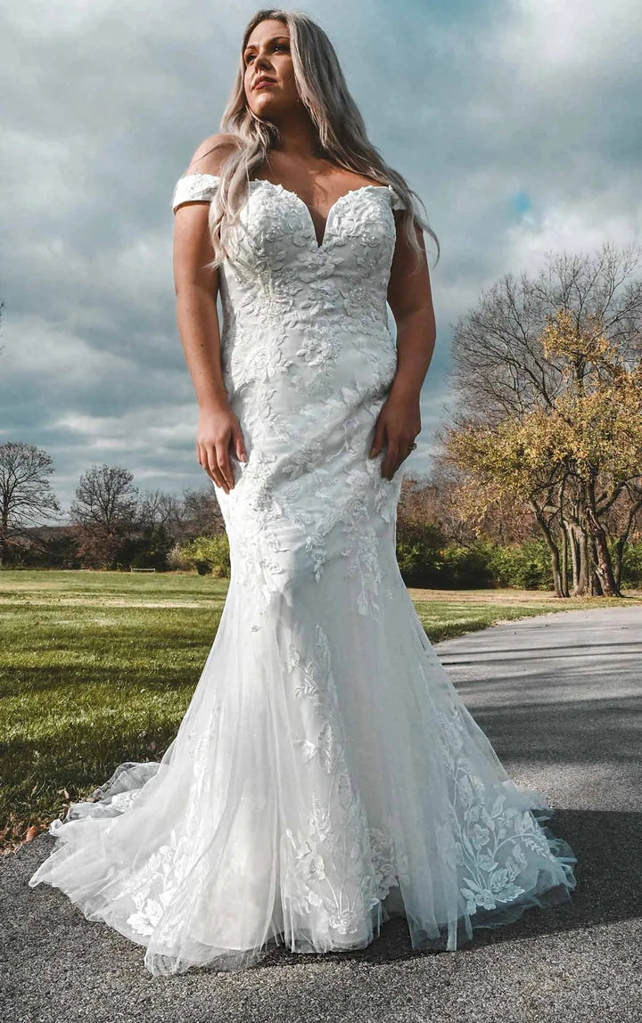 Woman in a white wedding dress standing outdoors on a cloudy day.
