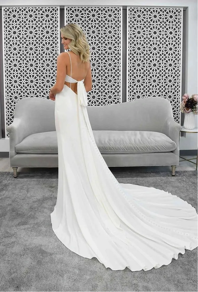 Woman in a white wedding dress standing in a modern room with a decorative wall panel.