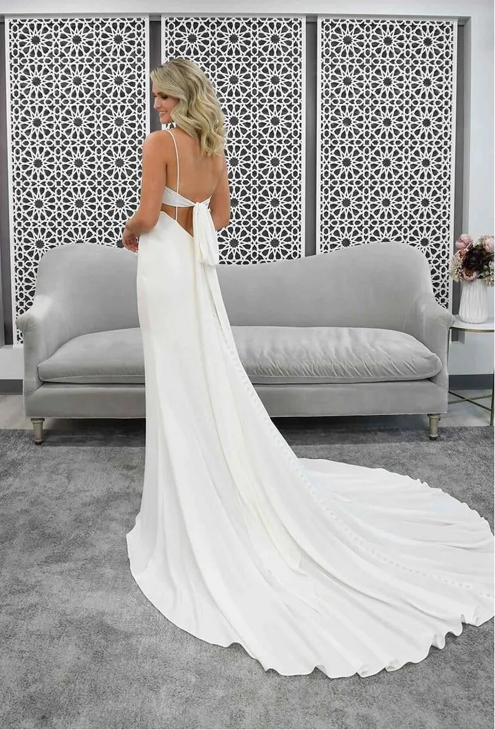 Woman in a white wedding dress standing in a modern room with a decorative wall panel.