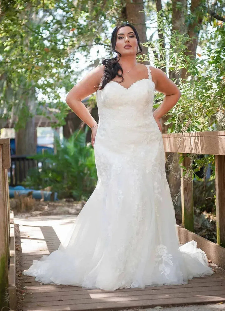 Woman in a white wedding dress standing on a wooden bridge with greenery in the background