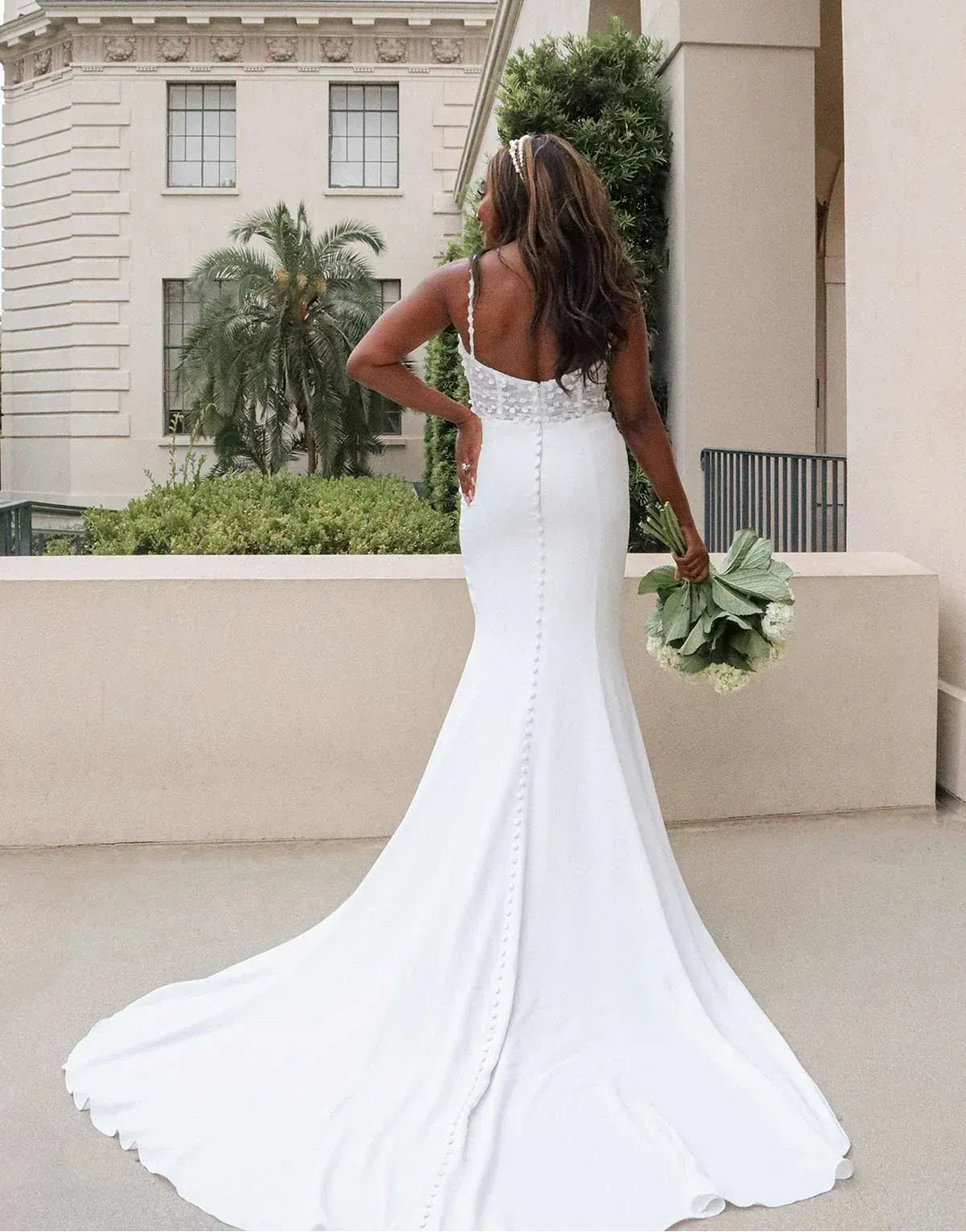 Woman in a white wedding dress holding a bouquet outdoors.