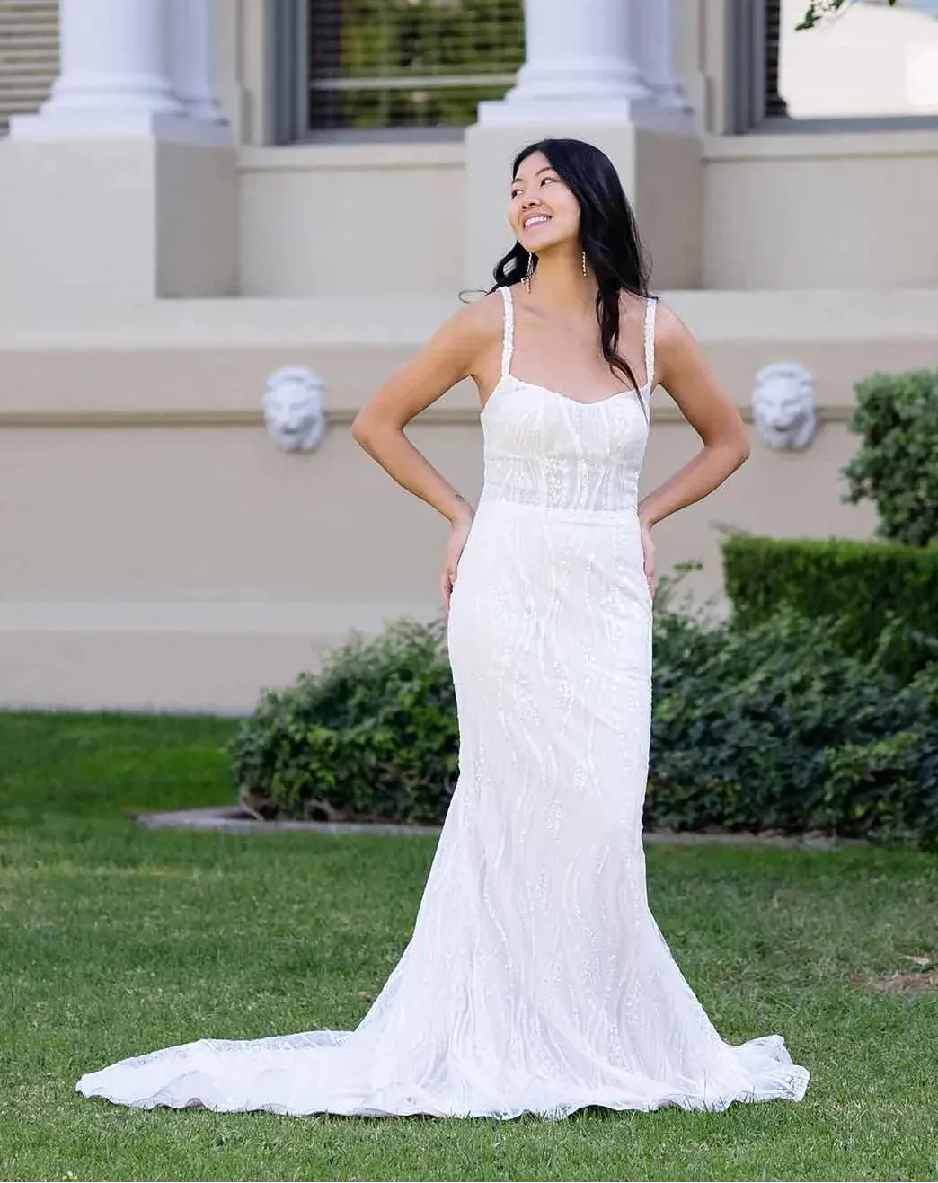Woman in a white dress standing in front of a classical building with columns.