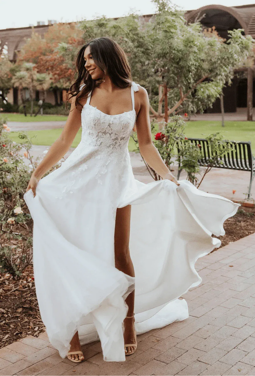 Woman in a white wedding dress with a high slit walking outdoors.