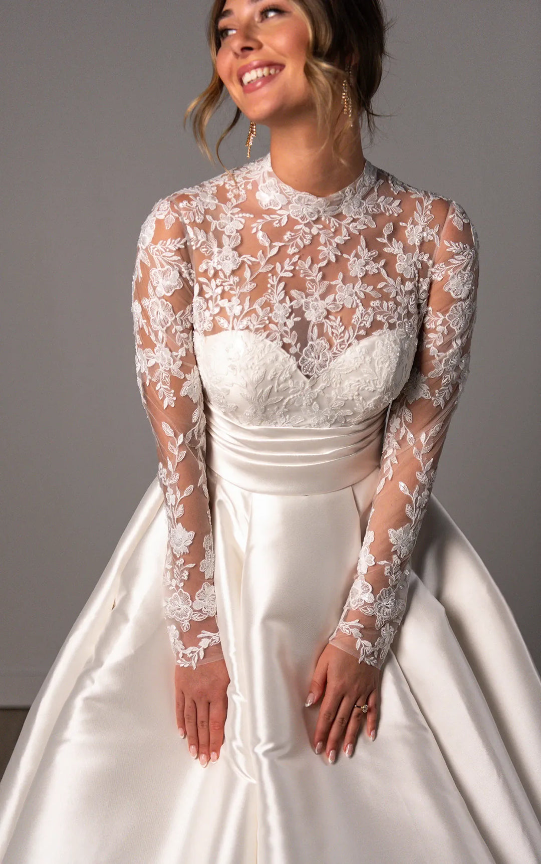 close up of stella york 8230 ivory mikado a-line wedding dress featuring a sheer lace bodice with a high neckline and long sleeves