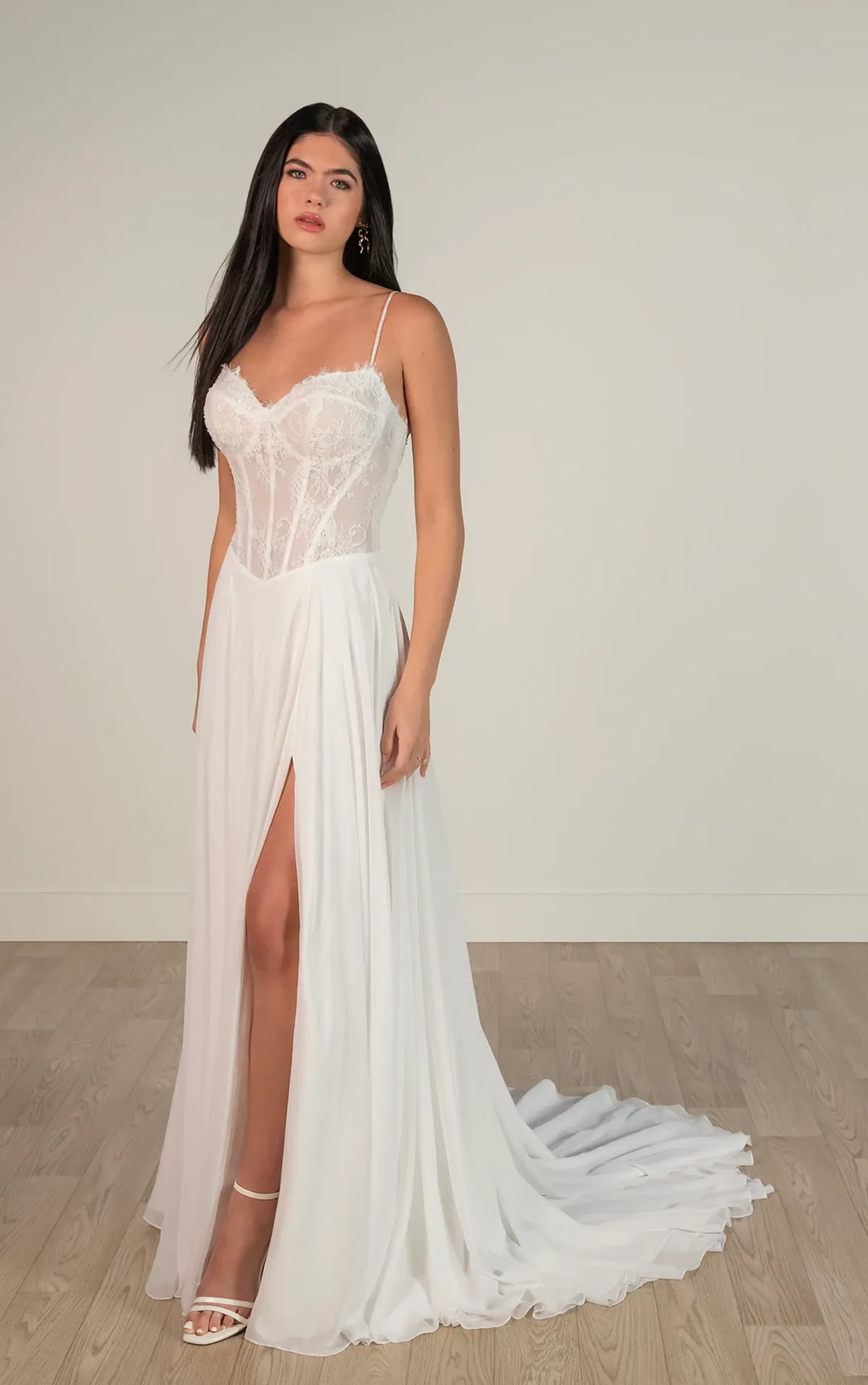 Woman wearing a white wedding dress with a high slit on a plain background