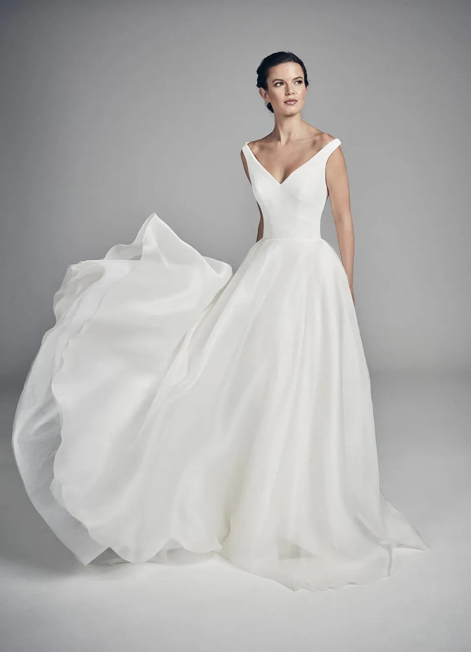 White wedding dress with a flowing skirt on a model against a gray background