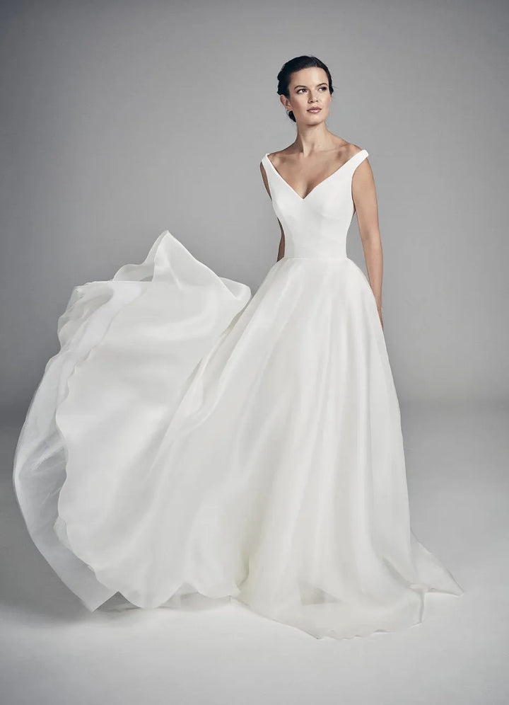 White wedding dress with a flowing skirt on a model against a gray background