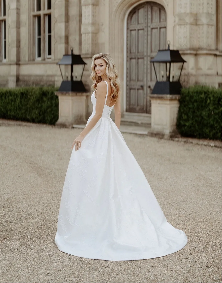 full back of suzanne neville bloomsbury ivory cloque a-line wedding dress with an open back and short train