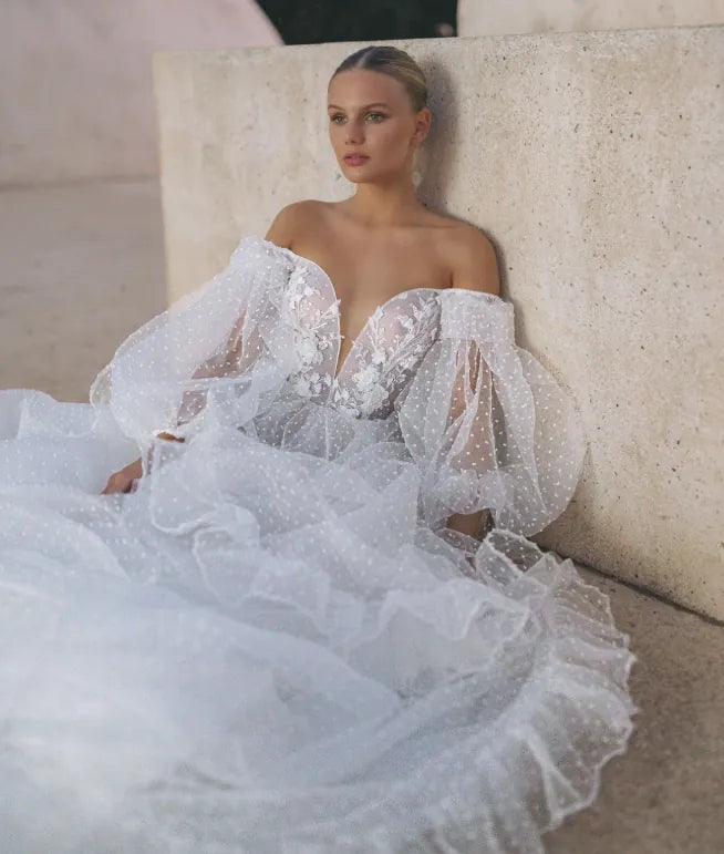 front of tal kedem sunset ivory dotted tulle a-line wedding dress, showing the off the shoulder sleeves and dotted tulle fabric