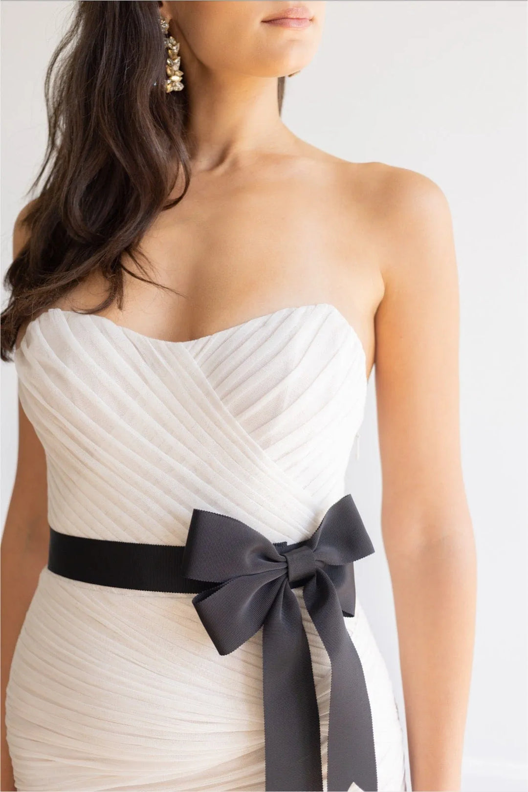 White strapless dress with a black ribbon bow on a plain background