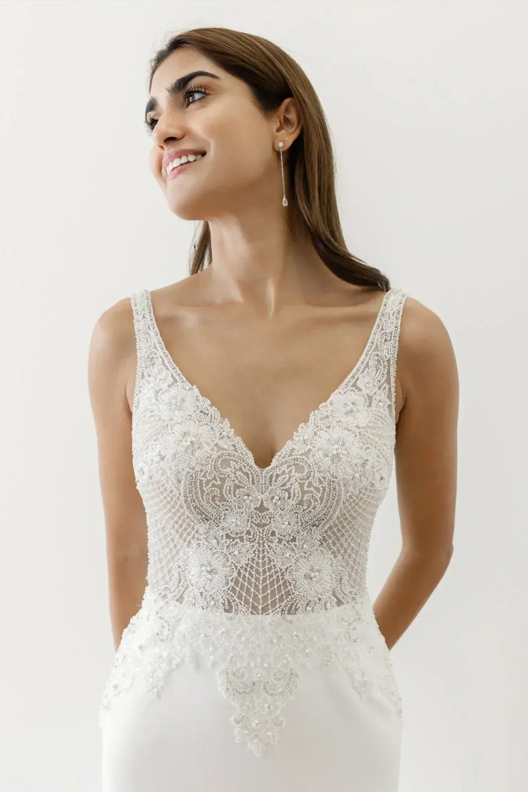 Woman wearing a white lace wedding dress against a plain background