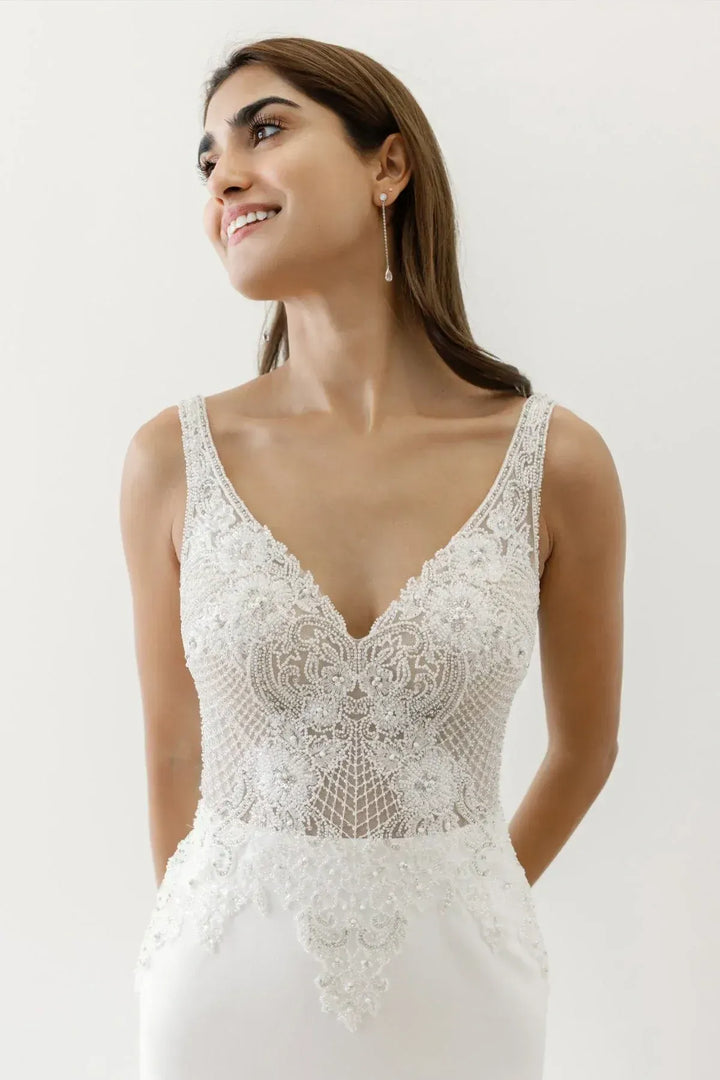 Woman wearing a white lace wedding dress against a plain background