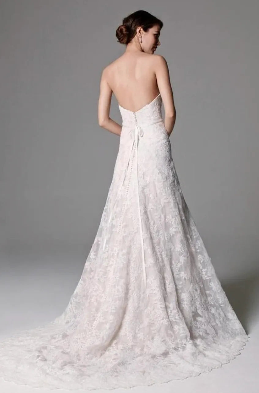 Woman wearing a white lace wedding dress with a gray background