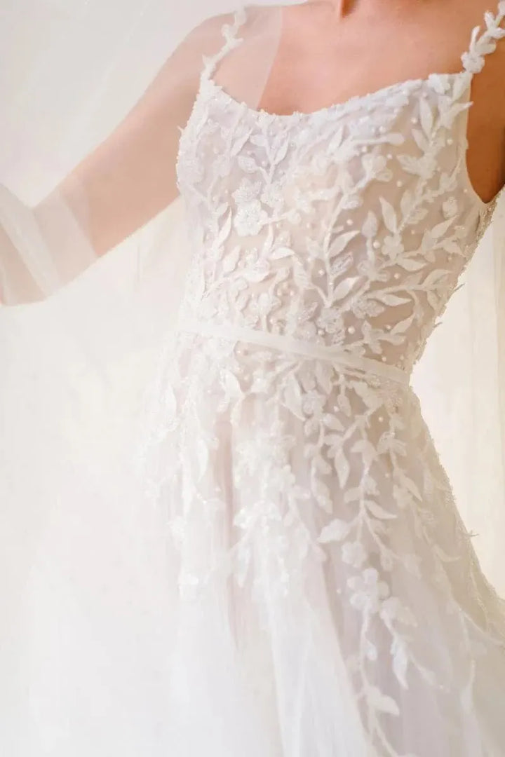 Close-up of a white lace wedding dress with a blurred background