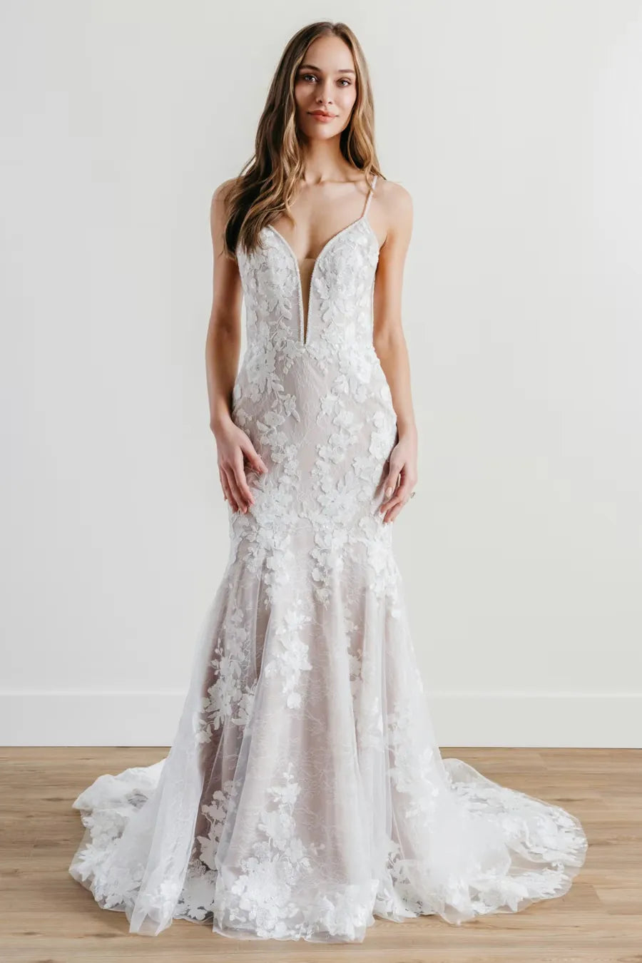 Woman wearing a white lace wedding dress on a plain background