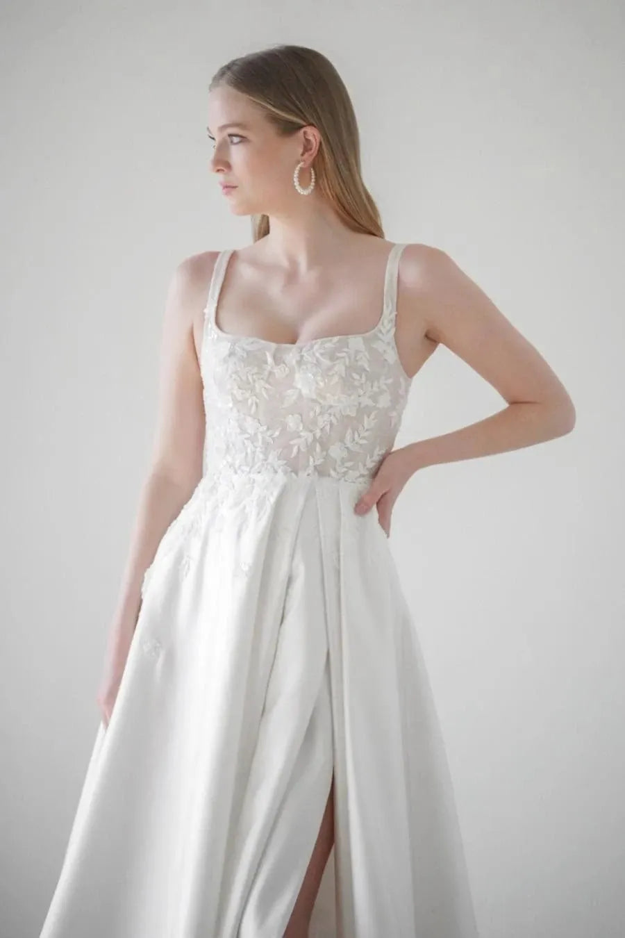 close up of watters eislyn ivory satin a-line wedding dress with a lace bodice and slit in the skirt