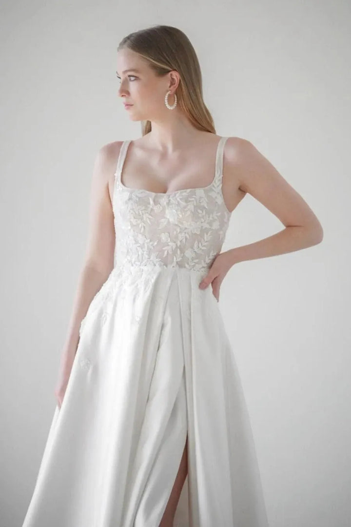 close up of watters eislyn ivory satin a-line wedding dress with a lace bodice and slit in the skirt
