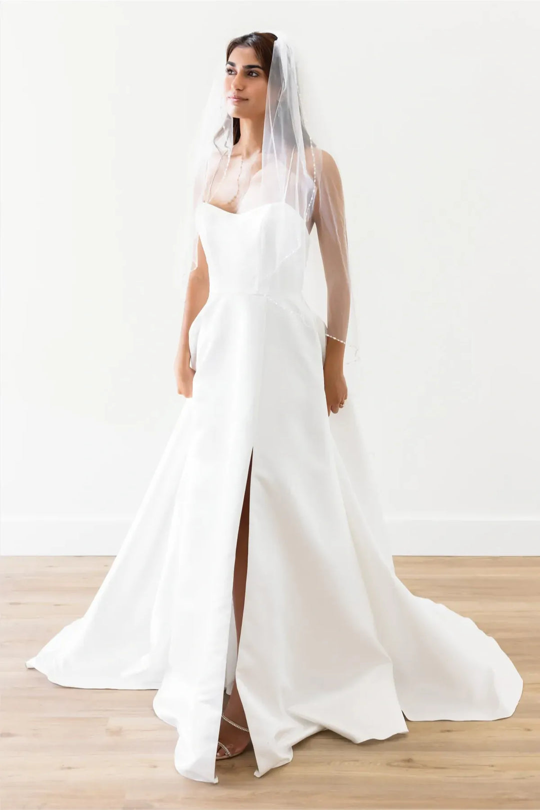front of locket by watters enola modest ivory satin a-line wedding dress showing the full front with the sweetheart neckline and slit in the skirt
