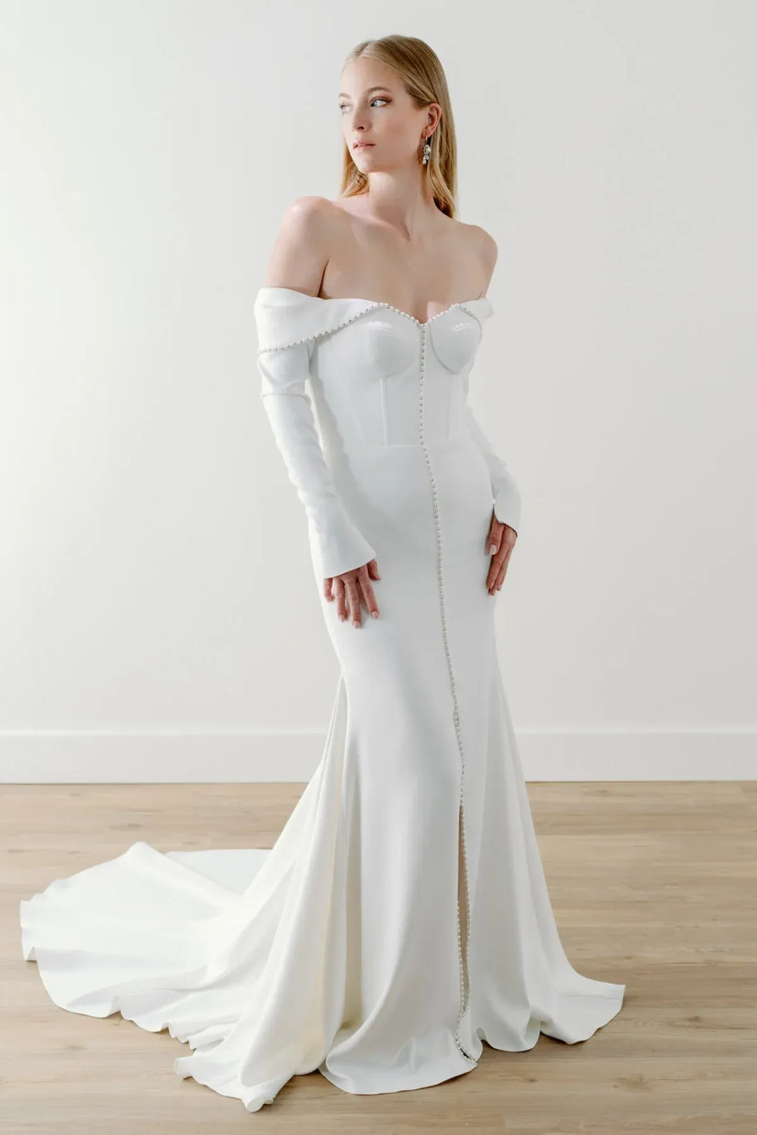 full front of watters everette ivory crepe fitted wedding dress with an off the shoulder long sleeve neckline trimmed with pearls