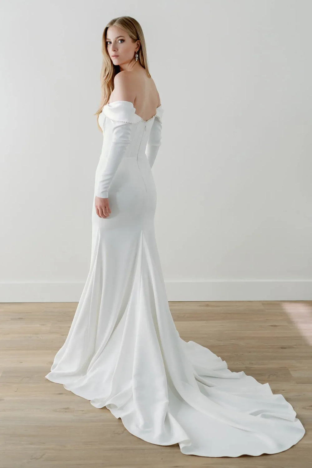 full front of watters everette ivory crepe fitted wedding dress with an off the shoulder long sleeve neckline and short train at the back