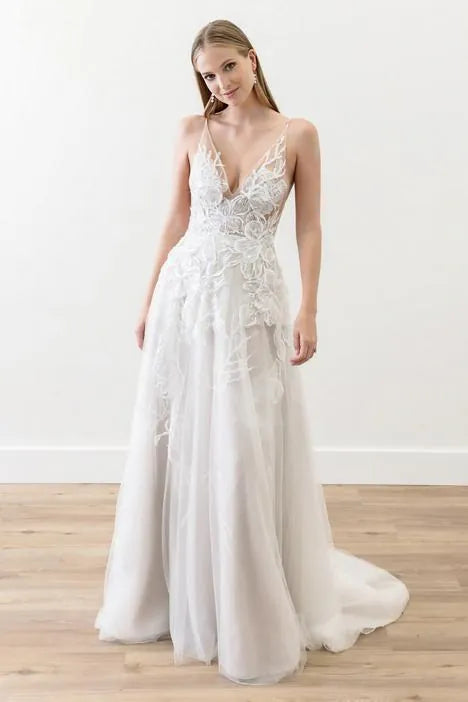 Woman wearing a white lace wedding dress on a plain background