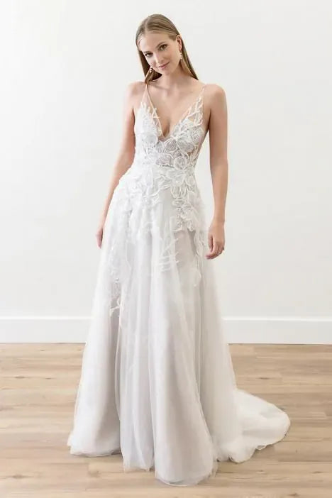 Woman wearing a white lace wedding dress on a plain background