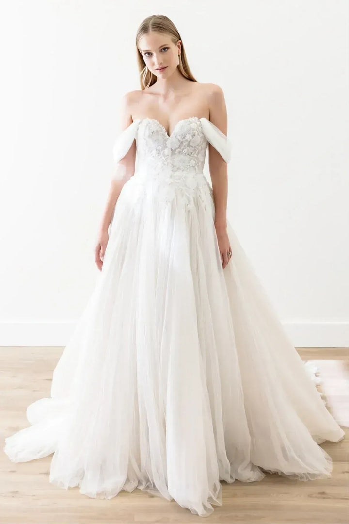 Woman wearing a white wedding dress with floral details on a light background