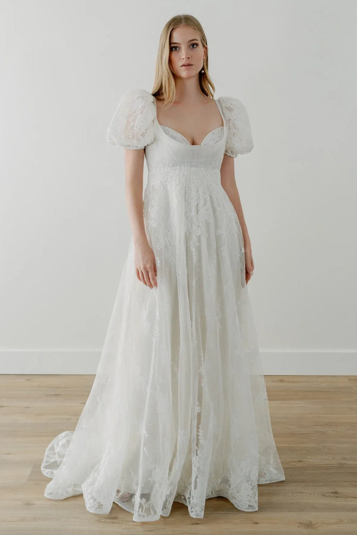 Woman wearing a white lace wedding dress on a plain background