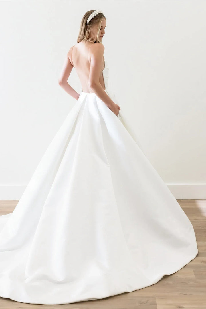 Woman wearing a white wedding dress with a plain background
