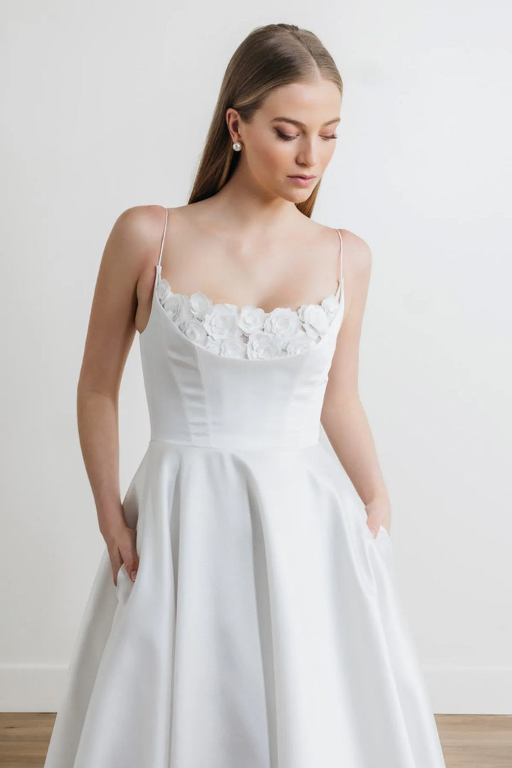 close up of watters hughes ivory mikado a-line wedding dress showing the scoop neck bodice with floral lace and thin straps