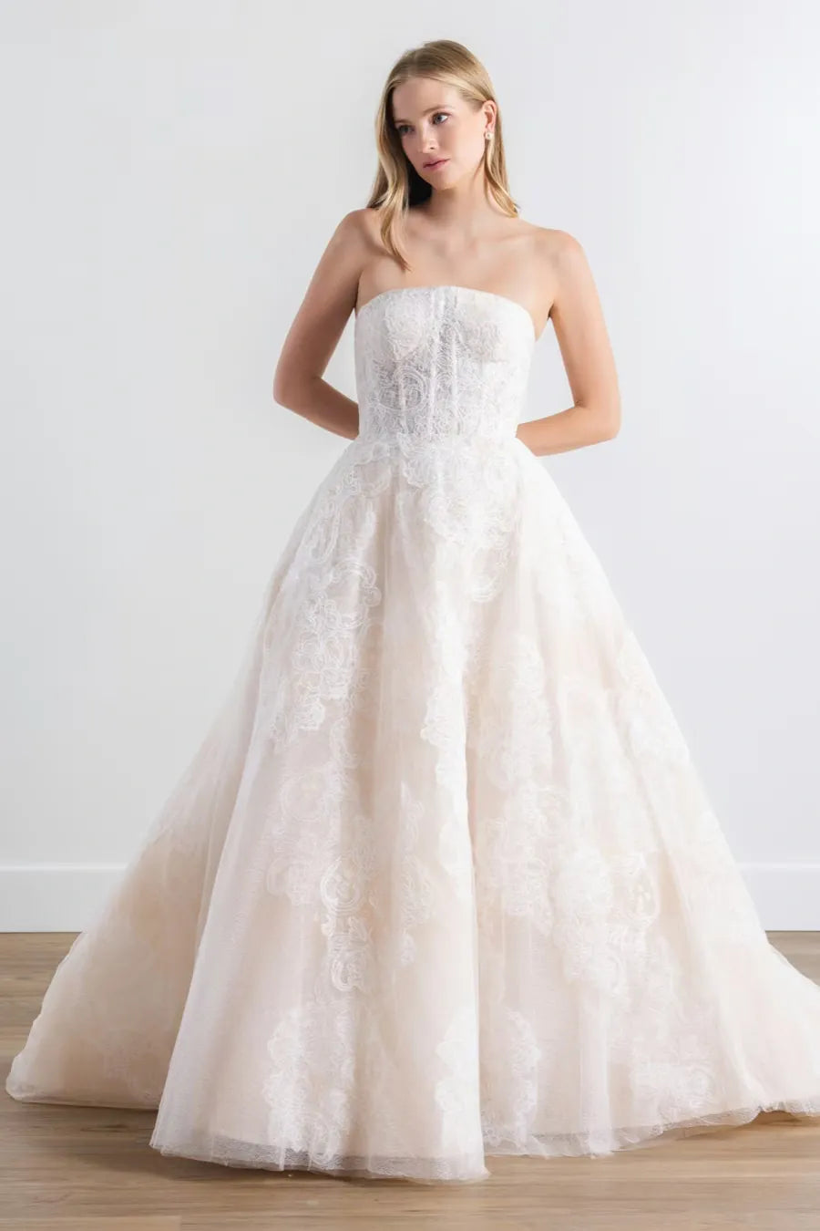 Woman wearing a strapless white wedding dress on a plain background