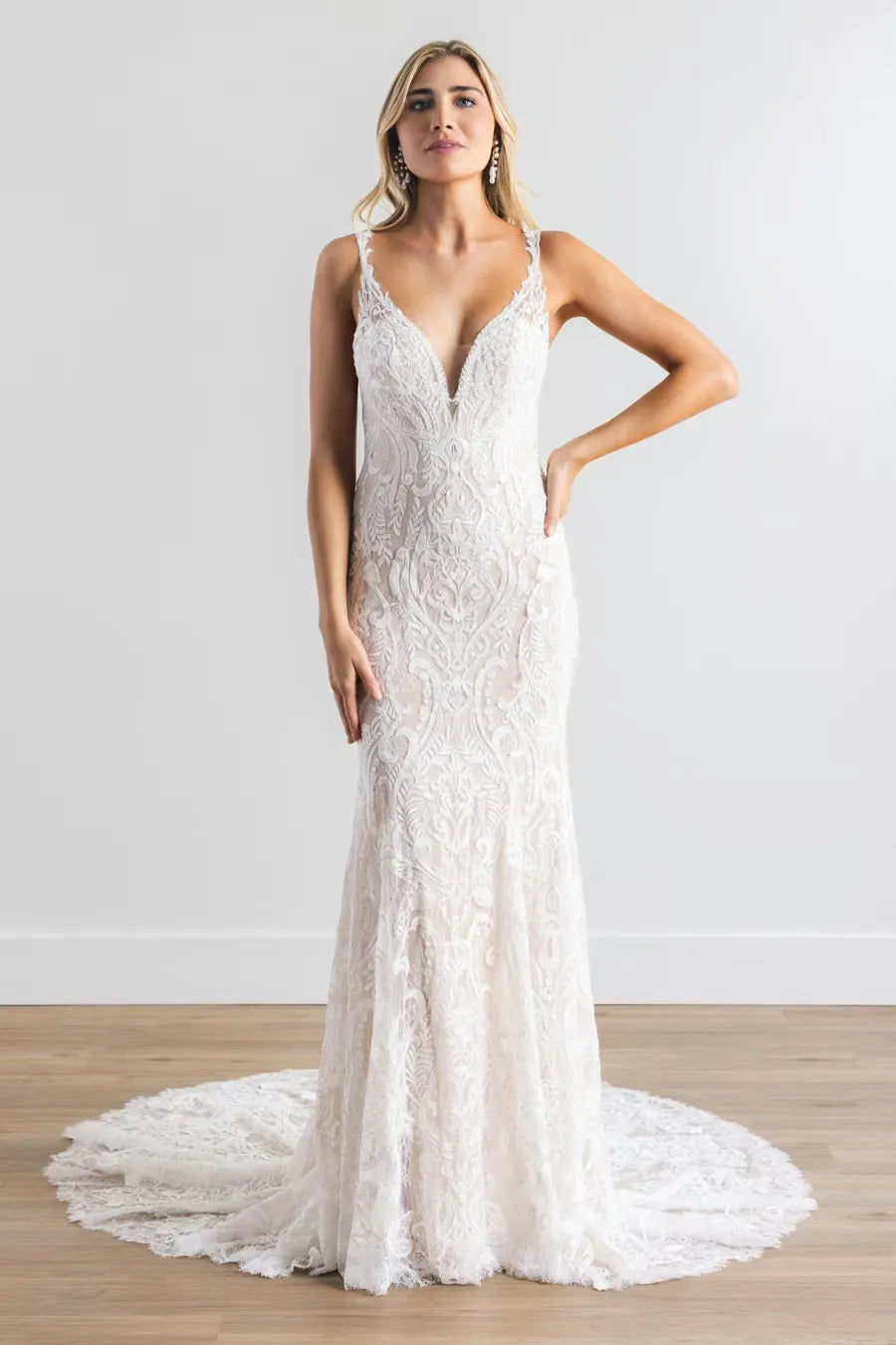 Woman wearing a white lace wedding dress on a plain background