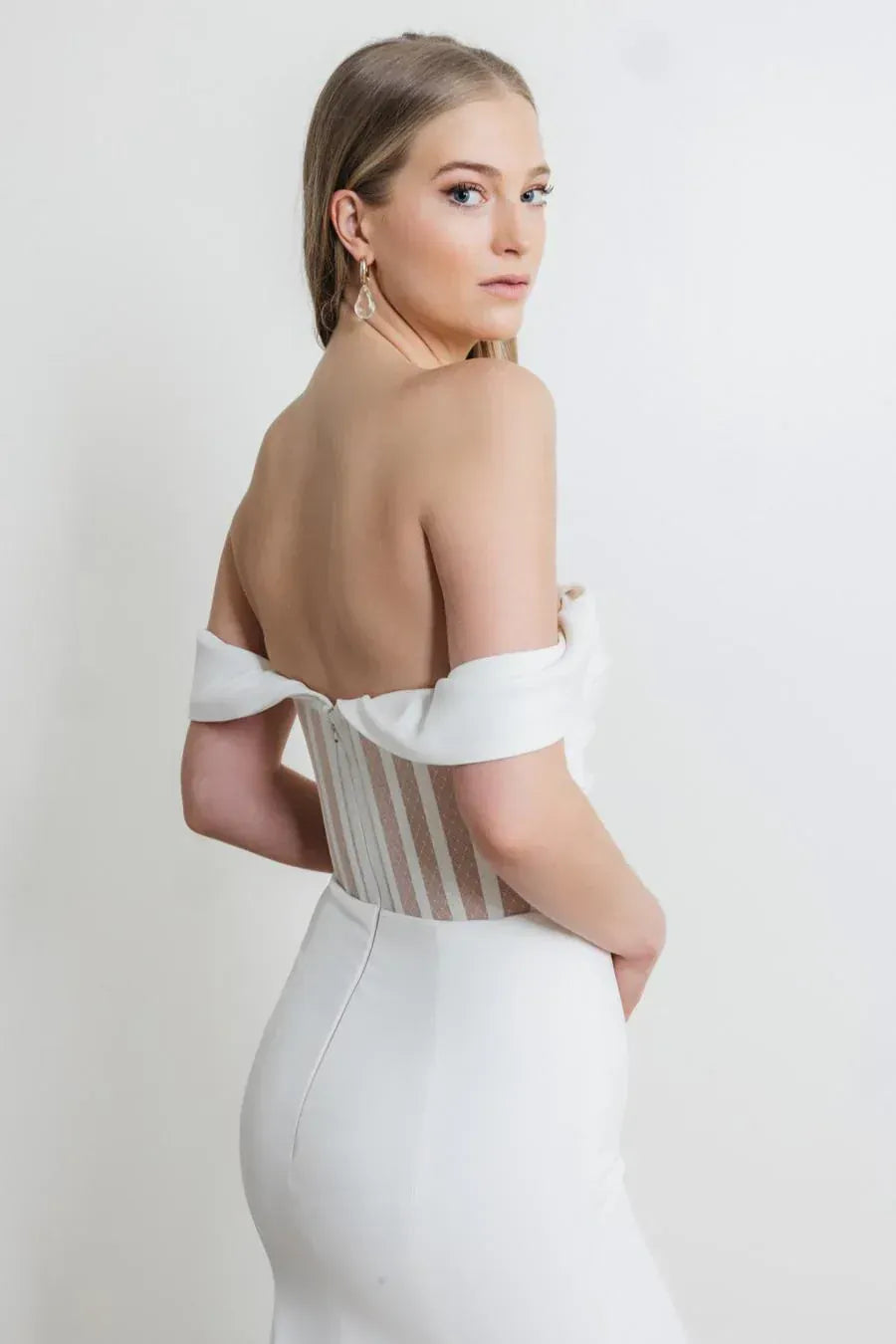 Woman wearing a white off-shoulder dress with a plain background