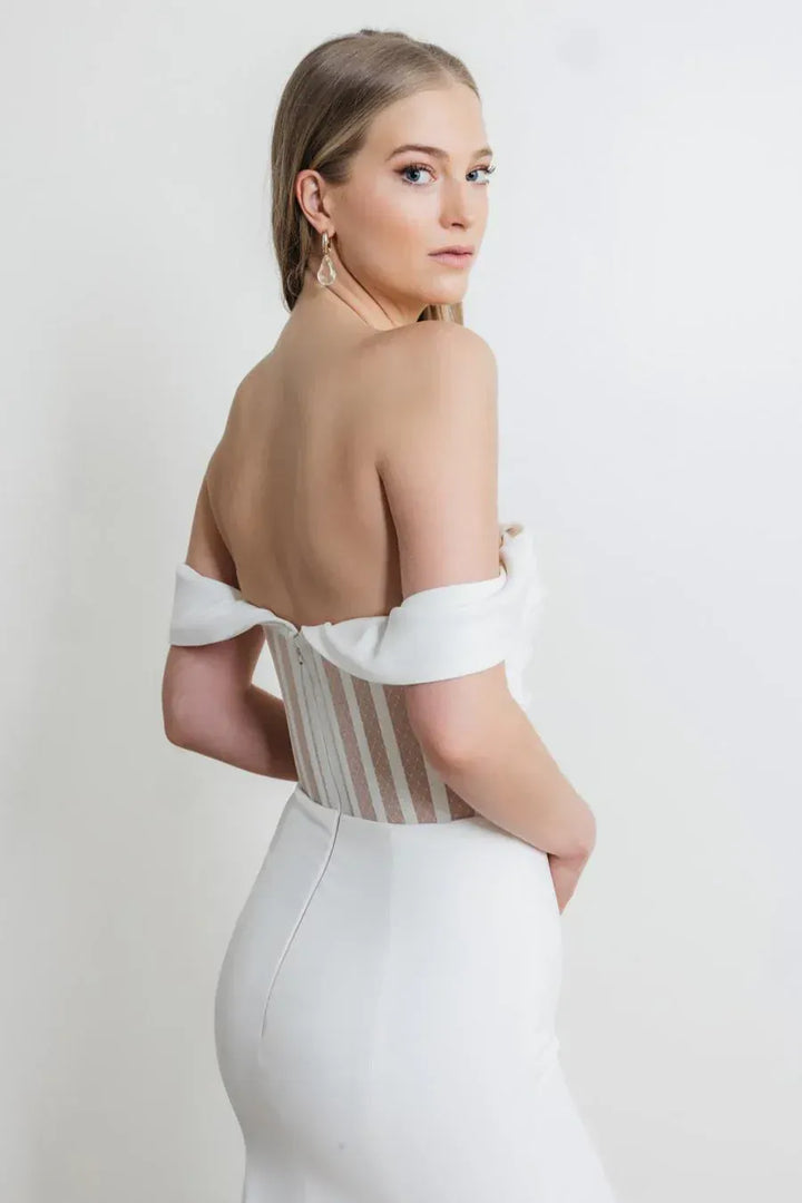Woman wearing a white off-shoulder dress with a plain background
