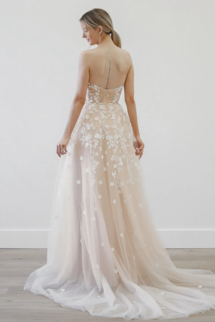Woman wearing a beige floral wedding dress with a white background