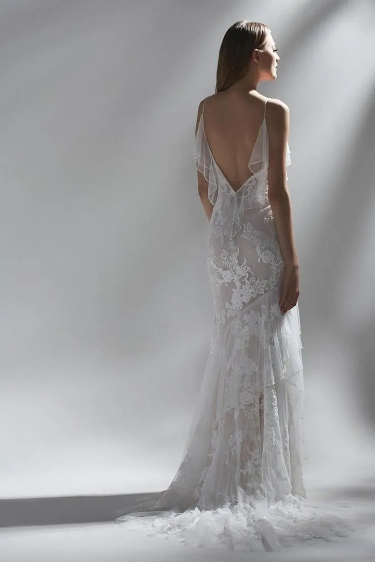 back of watters nephele blush lace fitted wedding dress with an open back framed by tulle ruffles that are mirrored on the skirt and short train