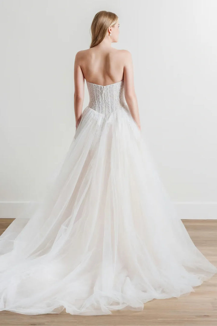 Woman wearing a strapless wedding dress with a plain background