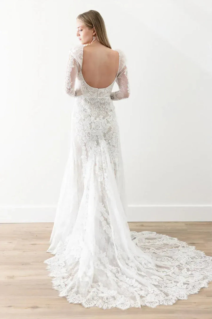 White lace wedding dress with open back on a wooden floor.