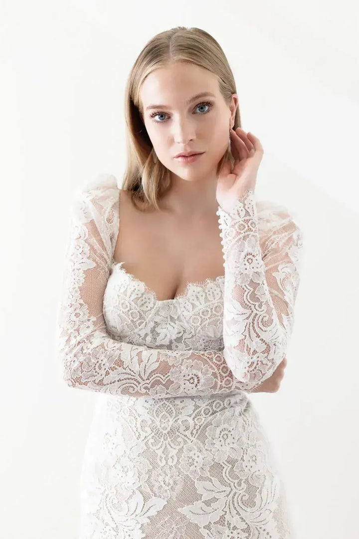 close up of watter ti amo nude lace fitted wedding dress featuring the sweetheart neckline and long sleeves on the bodice