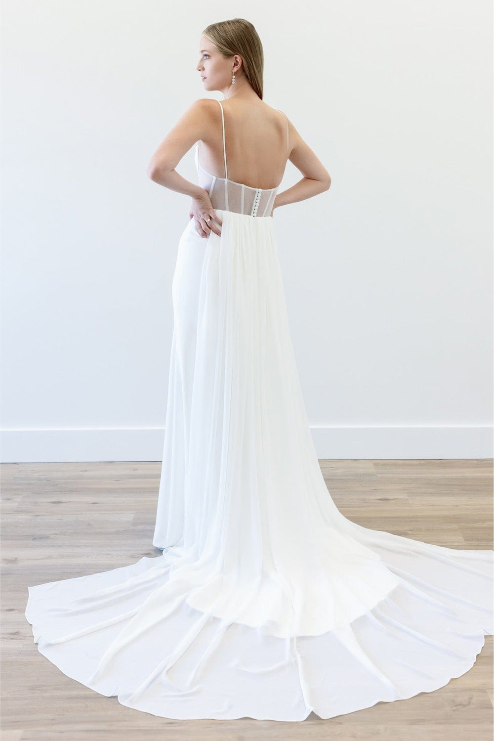 White wedding dress with a long train on a wooden floor.