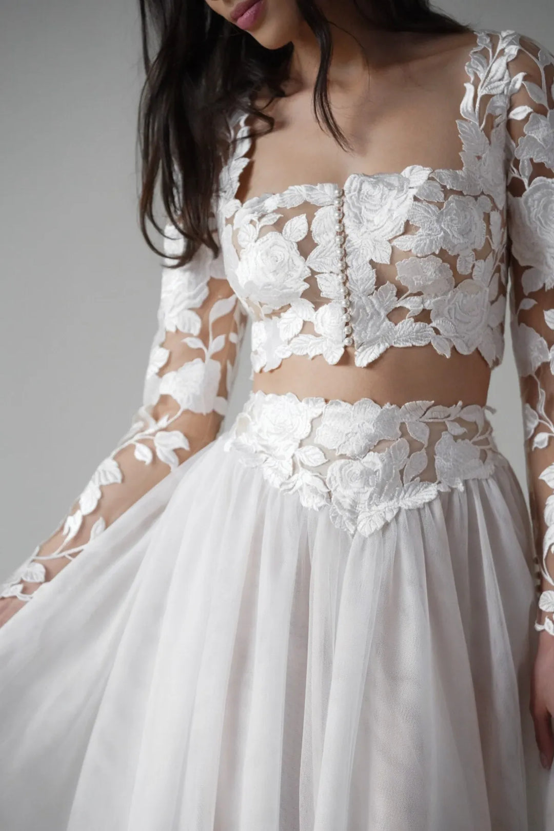 White lace wedding dress with long sleeves on a plain background