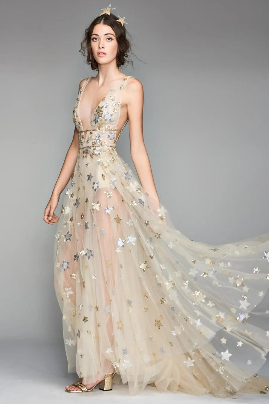 Woman wearing a long, flowing dress with star patterns on a gray background