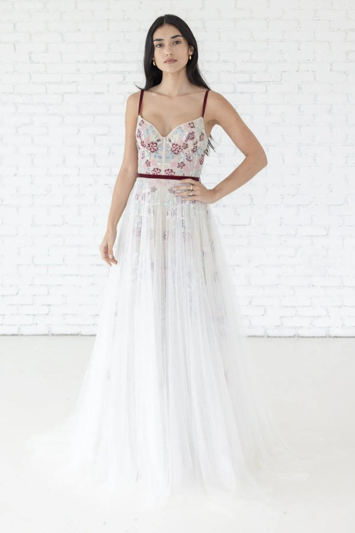 Woman wearing a floral dress against a white brick wall