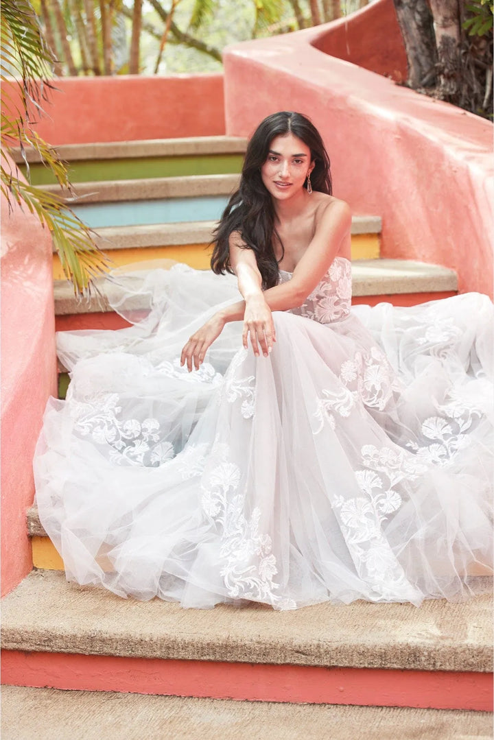 Woman in a white floral dress sitting on colorful steps outdoors