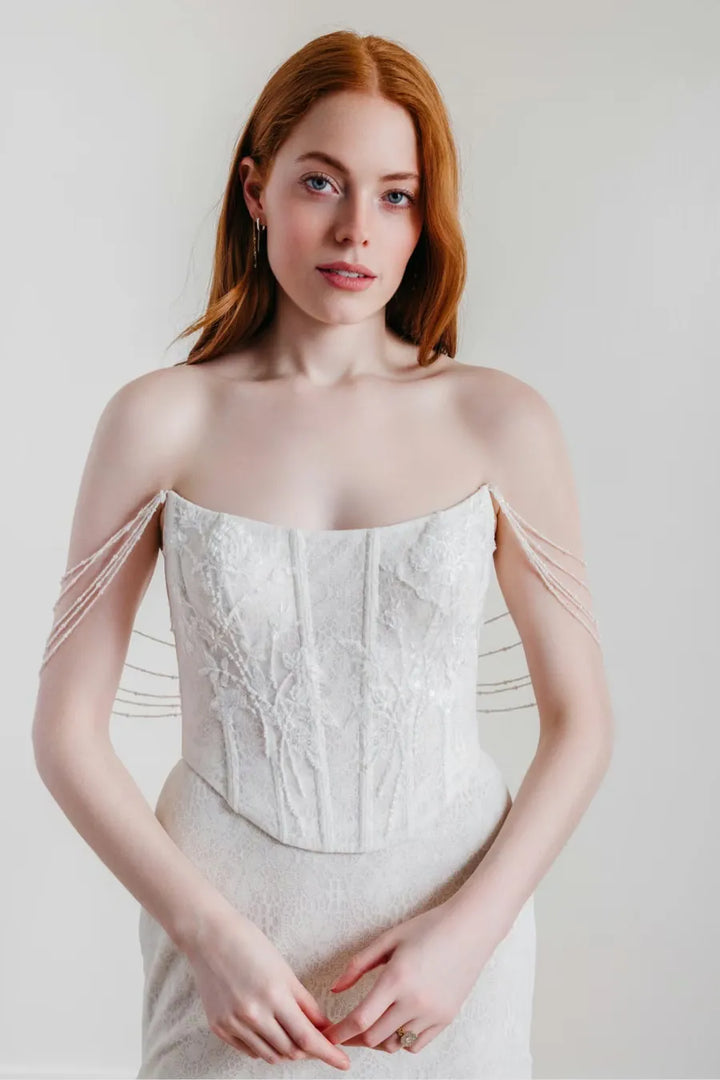 close up of willowby goldie ivory lace sheath wedding dress with a matching satin overskirt