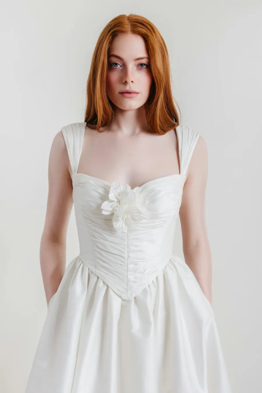 close up of willowby ingrid ivory dupioni a-line wedding dress with a drop waist and flower pin