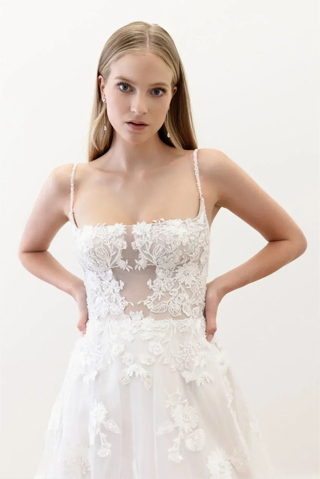 Model wearing a white lace wedding dress against a plain background